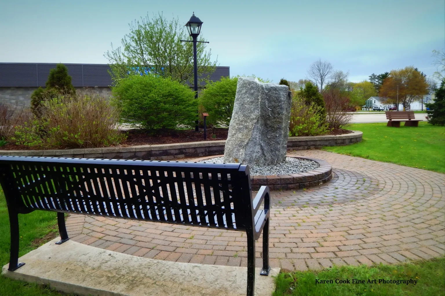 A paved seating area with a bench in a Kingston park