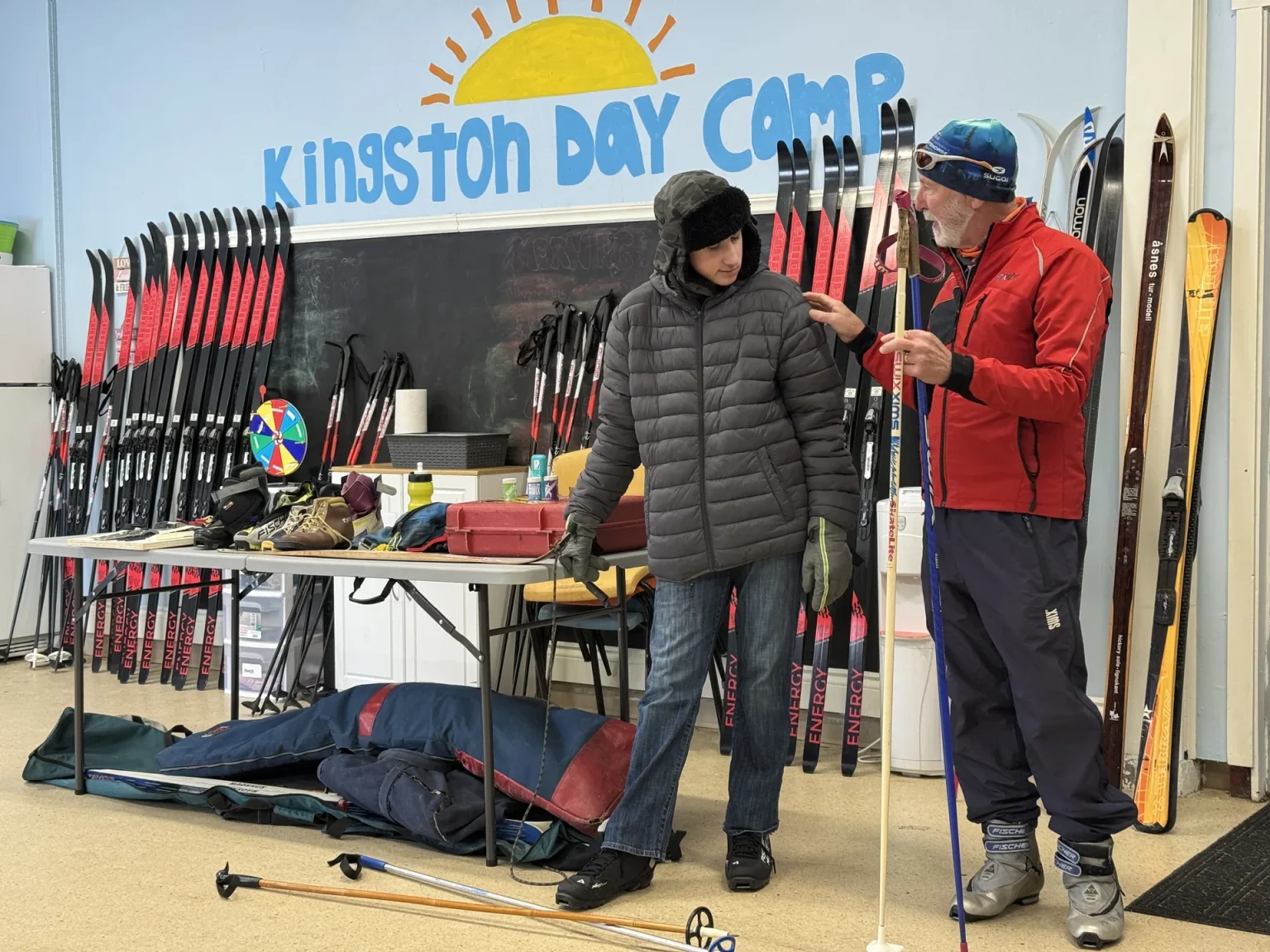 Getting fitted for skis in front of the Kingston Day Camp sign